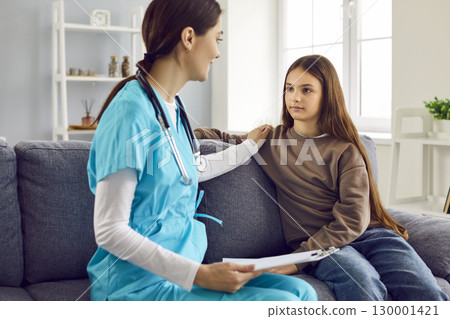 Friendly woman pediatrician talks to little girl and supports her during home visit 130001421