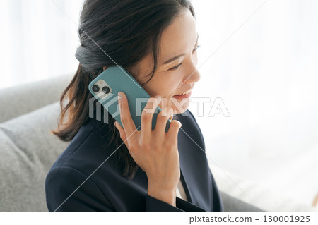 A woman in a suit making a phone call on the sofa 130001925