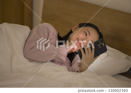 A woman watching a smartphone in bed 130002360