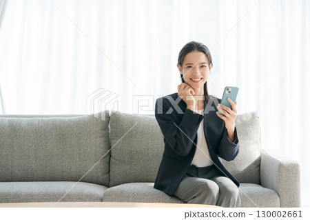 坐在沙發上使用智能手機的女人 坐在沙發上使用智能手機的女人 130002661
