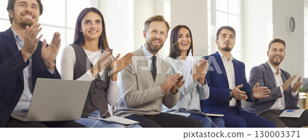Smiling business team in office clapping and showing support during corporate event or presentation. Smiling business team in office clapping and showing support during corporate event or presentation. 130003371