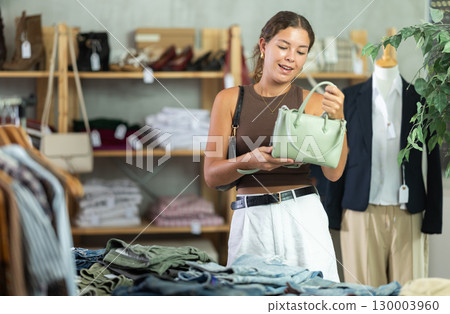 Woman choosing handbags in the store 130003960