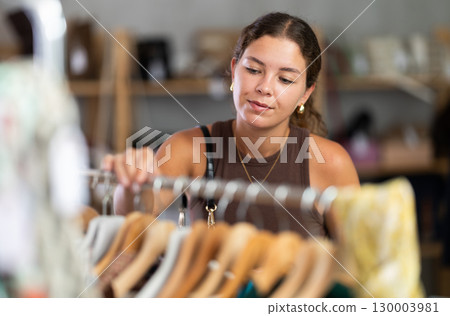 Female customer in store chooses summer clothes. Female customer in store chooses summer clothes. 130003981