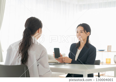 一位女商人在客廳講解智慧型手機 130004001