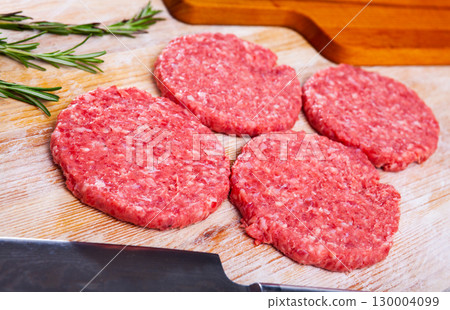 Raw meat burger cutlet with greens on wooden surface 130004099