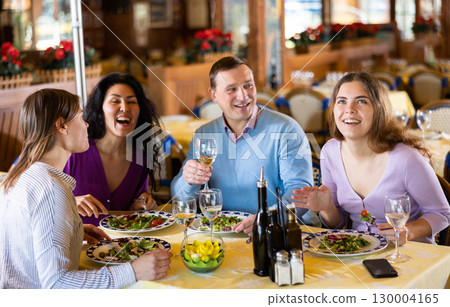 Man and women smiling and talking while eating in restaurant 130004165