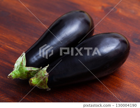 Fresh eggplants on wooden surface in home kitchen Fresh eggplants on wooden surface in home kitchen 130004190