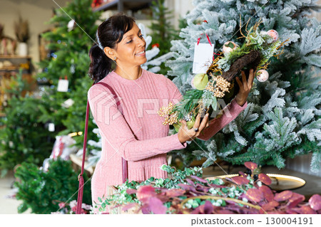 Positive latin american woman chooses a Christmas wreath Positive latin american woman chooses a Christmas wreath 130004191