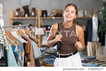 Girl is intently examining sales area of womens clothing store and looking for something 130004237