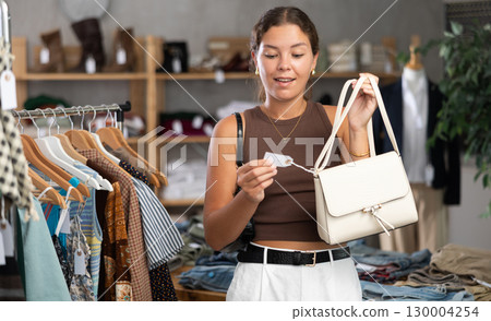 Woman choosing handbags in the store 130004254