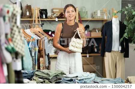 Woman choosing handbags in the store 130004257
