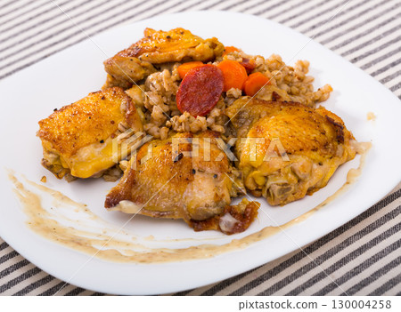 Tasty barley groats with chicken thighs at plate on table Tasty barley groats with chicken thighs at plate on table 130004258