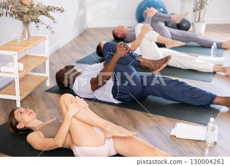 Young woman doing yoga in group in studio 130004261