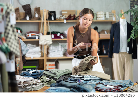 Woman scans pants on phone in store 130004280