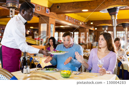 Wife and husband arguing with waiter in restaurant Wife and husband arguing with waiter in restaurant 130004283