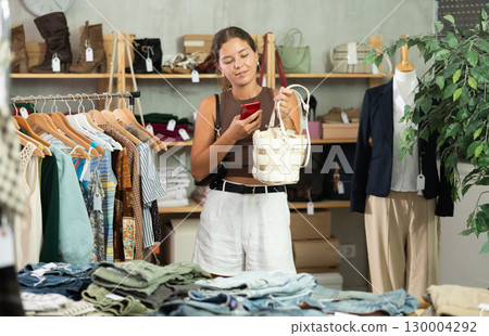 While shopping, girl scans barcode on label of handbag While shopping, girl scans barcode on label of handbag 130004292