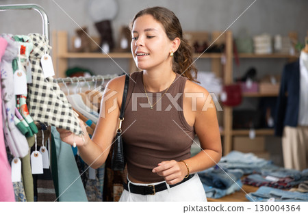Girl customer choose scarf in store, and buyer carefully examines product. Girl customer choose scarf in store, and buyer carefully examines product. 130004364