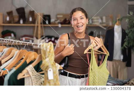 Young woman choosing lazy clothes in boutique 130004378