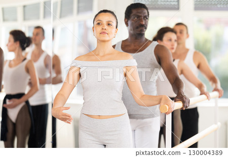 Asian female ballet enthusiast learning first position at barre 130004389