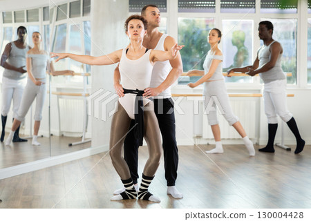 Ballet partners mastering paired technique during group class 130004428