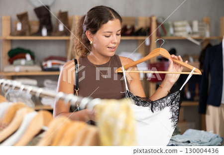 Young woman choosing a top near a hanger 130004436
