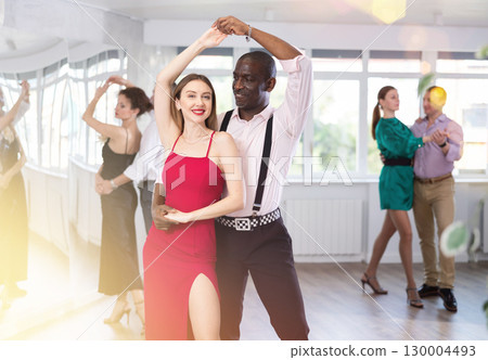 Woman with African man dancing waltz in couple during lesson at studio 130004493