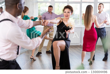 Woman and man dancing foxtrot in pair during group dance party 130004496