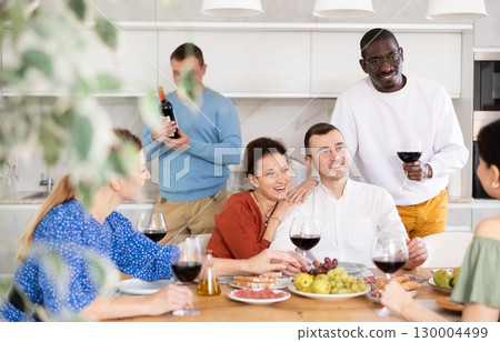 Cheerful friends enjoying wine and conversations in home kitchen Cheerful friends enjoying wine and conversations in home kitchen 130004499