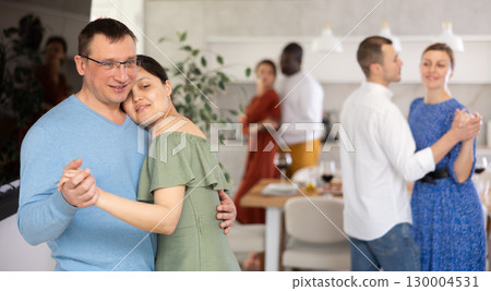 Men and women of different nationalities having fun dancing slow dance at house party 130004531