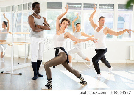 Focused choreographer watching female ballet dancer movements during group practice Focused choreographer watching female ballet dancer movements during group practice 130004537
