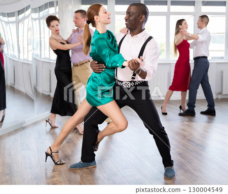 Dance training in group - men and women of different nationalities and different ages dance tango or bachata in dance studio 130004549