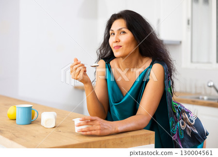 Portrait of woman eating yoghurt at home Portrait of woman eating yoghurt at home 130004561