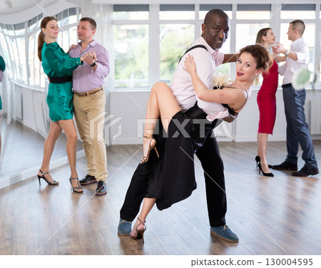 Woman dances incendiary tango with African man partner during choreography lesson Woman dances incendiary tango with African man partner during choreography lesson 130004595