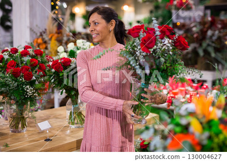 Hispanic woman selecting flowers in store Hispanic woman selecting flowers in store 130004627