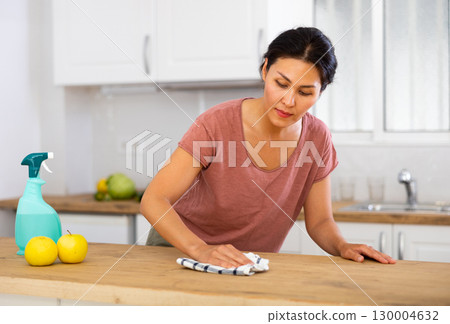 Woman cleaning table with rag at home 130004632