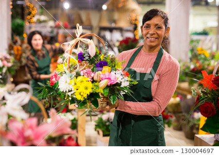 Smiling latin american florist woman stands with flowers Smiling latin american florist woman stands with flowers 130004697