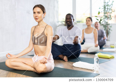 Young woman doing yoga in group in studio 130004709