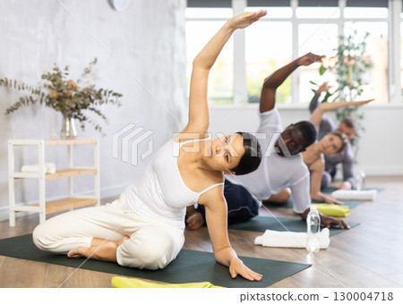 Asian woman doing stretching asana Parsva Sukhasana in yoga studio Asian woman doing stretching asana Parsva Sukhasana in yoga studio 130004718