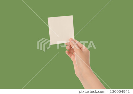 Hand holds untitled paper against a green backdrop Hand holds untitled paper against a green backdrop 130004941