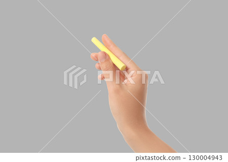 A hand grips a yellow chalk piece in preparation for creativity 130004943