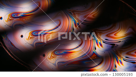 Glow paint blur. Iridescent oil. Colorful gasoline round light lens on black background. Fuel curve blending liquid abstract texture. Glow paint blur. Iridescent oil. Colorful gasoline round light lens on black background. Fuel curve blending liquid abstract texture. 130005193