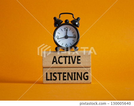 Listen actively symbol. Wooden blocks with words Listen actively. Beautiful orange background with alarm clock. Business and Active listening concept. Copy space. 130005640