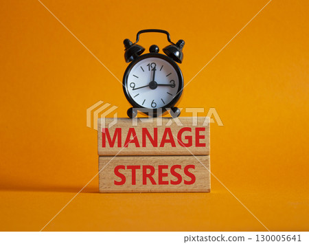 Manage stress symbol. Concept word Manage stress on wooden blocks. Beautiful orange background with alarm clock. Business and Manage stress concept. Copy space 130005641