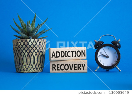 Addiction Recovery symbol. Concept words Addiction Recovery on wooden blocks. Beautiful blue background with alarm clock and succulent. Medicine and Addiction Recovery concept. Copy space. 130005649