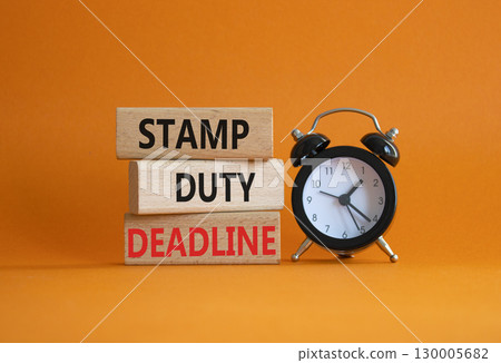 Stamp Duty Deadline symbol. Concept words Stamp Duty Deadline on wooden blocks. Beautiful orange background with alarm clock. Business and Stamp Duty Deadline concept. Copy space. 130005682