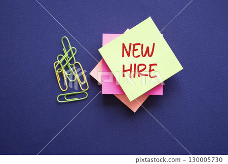 New Hire symbol. Yellow sticky note with concept words New Hire. Beautiful deep blue background. Business and New Hire concept. Copy space. 130005730