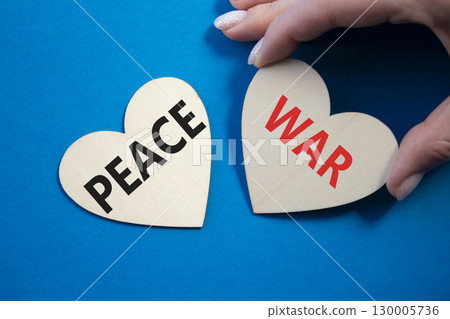War or Peace symbol. Concept word War or Peace on wooden hearts. Businessman hand. Beautiful blue background. Business and War or Peace concept. Copy space War or Peace symbol. Concept word War or Peace on wooden hearts. Businessman hand. Beautiful blue background. Business and War or Peace concept. Copy space 130005736