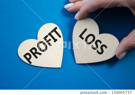 Profit or Loss symbol. Concept word Profit or Loss on wooden hearts. Businessman hand. Beautiful blue background. Business and Profit or Loss concept. Copy space Profit or Loss symbol. Concept word Profit or Loss on wooden hearts. Businessman hand. Beautiful blue background. Business and Profit or Loss concept. Copy space 130005737