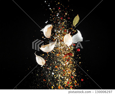 AI generated Coriander root garlic and black pepper explode in both whole and powdered forms from opposite sides of frame colliding dramatically in center against pure black background 130006297