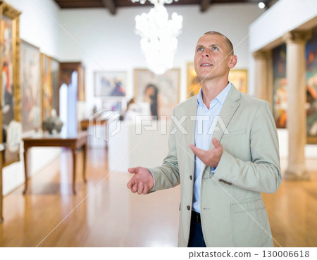 AI generated An elegant curator stands at the frame edge gesturing toward a spacious museum gallery filled with art and artifacts. The sophisticated atmosphere conveys cultural heritage, artistic 130006618